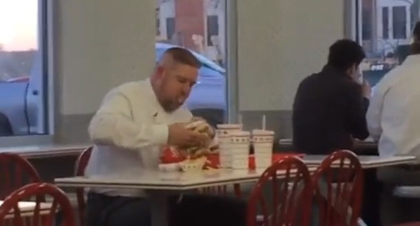 Un homme dévore ses burgers dans un fast-food