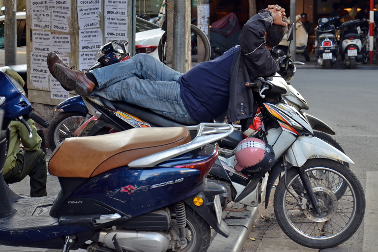 Un homme fait une petite sieste en conduisant son scooter