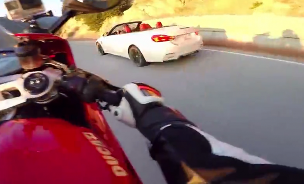 Un motard en duel une BMW sur une route sinueuse