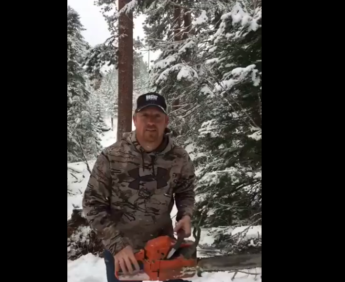 Un homme coupe son sapin de noël à l’aide d’un fusil