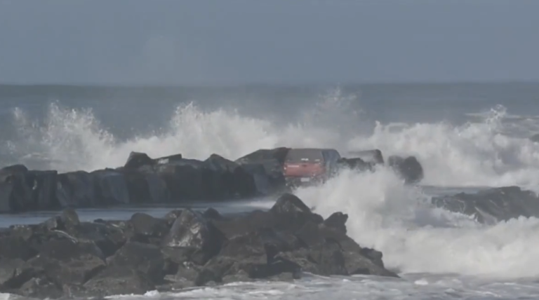 Une voiture sur une jetée au milieu des vagues