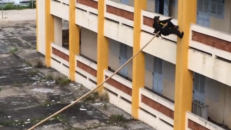 La police vietnamienne escalade un immeuble avec une perche