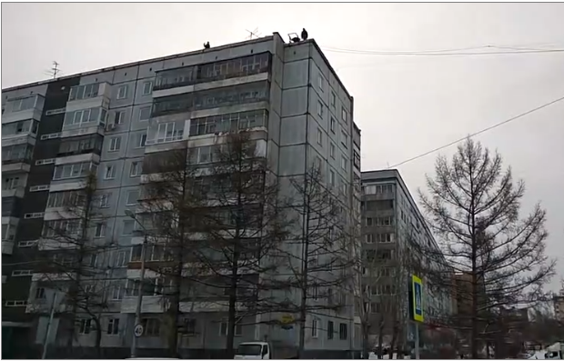 Ils chargent un camion en balançant de la marchandise du toit d’un immeuble en Russie