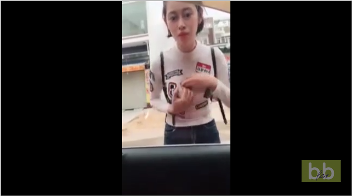 Une fille utilise le reflet de la vitre teintée d’une voiture pour se refaire une beauté