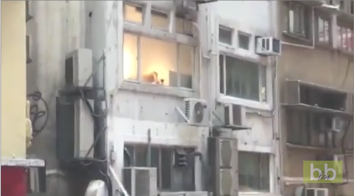 Des passants regardent un couple en pleine action à la fenêtre de leur appartement