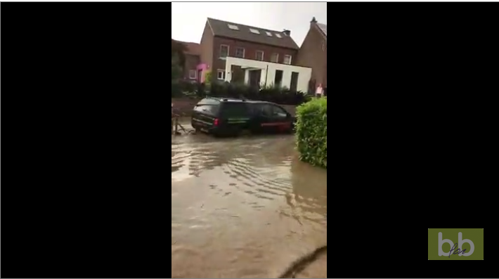 Une femme s’énerve contre une voiture qui passe dans la rue inondée devant chez elle en Belgique