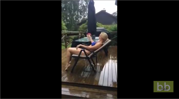 Un enfant ne comprend pas pourquoi sa mère bronze en bikini sur la terrasse alors qu’il pleut