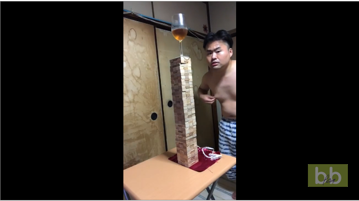 Il enlève une nappe sous une pile de Jenga sans faire tomber un verre de vin