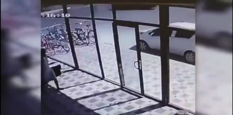 Une femme se fait troller par une porte vitrée