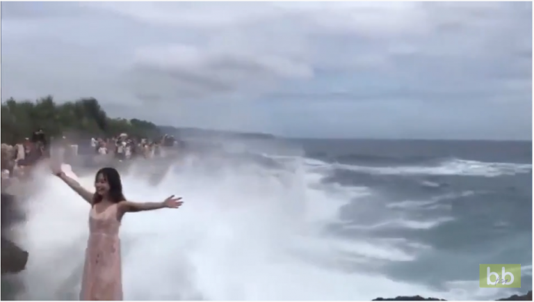 Cette fille veut faire la photo parfaite avec une vague derrière elle